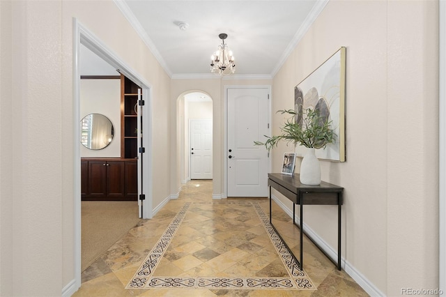 entryway featuring inlaid floor details, arched walkways, a chandelier, baseboards, and ornamental molding
