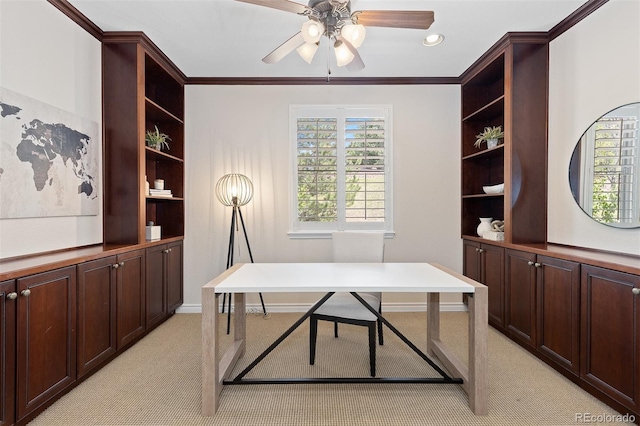 office area with a ceiling fan, light colored carpet, built in features, crown molding, and baseboards
