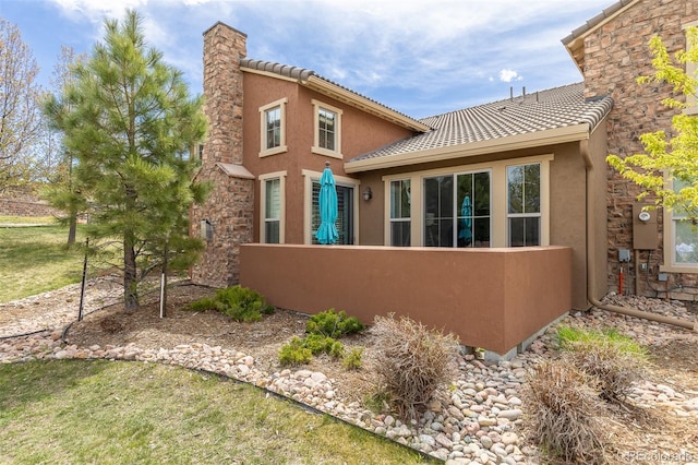 back of property featuring stucco siding, a tile roof, and fence