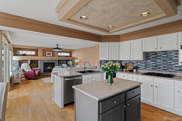 9249 Fox Fire Dr, Highlands Ranch, CO 80129 - kitchen with black gas cooktop, dishwasher, white cabinetry, a kitchen island, and decorative backsplash