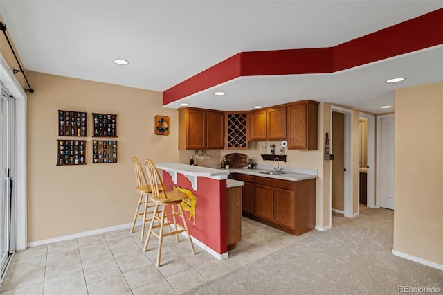 9249 Fox Fire Dr, Highlands Ranch, CO 80129 - kitchen with a breakfast bar, brown cabinetry, a peninsula, light countertops, and recessed lighting