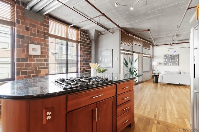 kitchen with stainless steel gas cooktop, decorative backsplash, light wood-type flooring, and dark stone counters