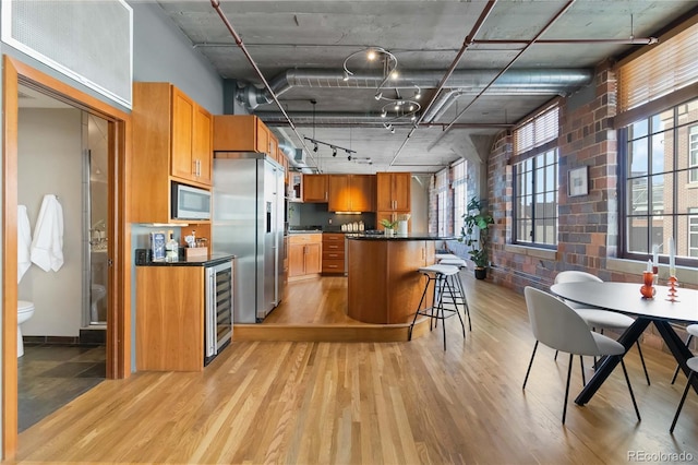 kitchen with light hardwood / wood-style flooring, stainless steel appliances, a center island, and brick wall