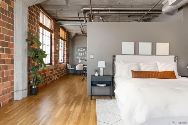 bedroom featuring hardwood / wood-style flooring and brick wall