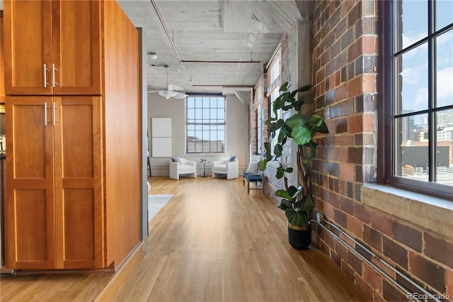 corridor with light hardwood / wood-style flooring and brick wall