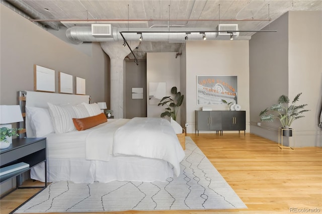 bedroom with hardwood / wood-style floors and track lighting