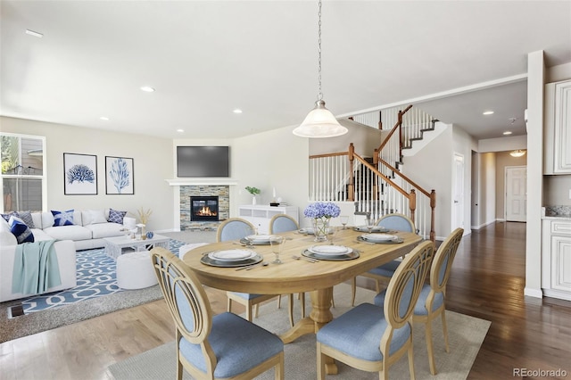 3823 Horiuchi St, Brighton, CO 80601 - dining space with stairs, dark wood-style flooring, a stone fireplace, and recessed lighting