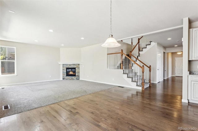 3823 Horiuchi St, Brighton, CO 80601 - unfurnished living room featuring dark wood-style flooring, baseboards, stairway, a stone fireplace, and recessed lighting