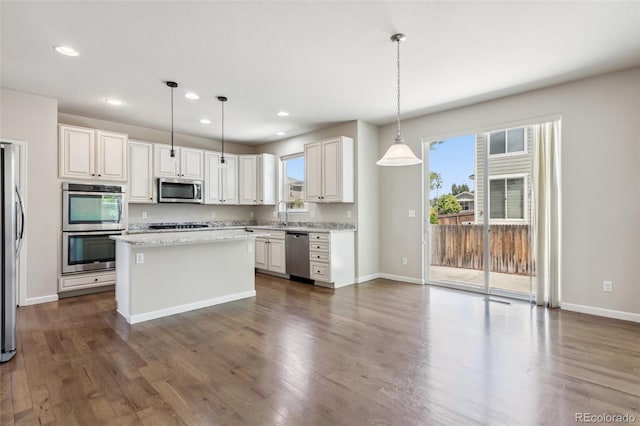 3823 Horiuchi St, Brighton, CO 80601 - kitchen with stainless steel appliances, dark wood finished floors, white cabinetry, a center island, and recessed lighting