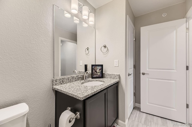 23545 E Platte Dr Unit C, Aurora, CO 80016 - bathroom featuring vanity, toilet, a textured wall, and baseboards