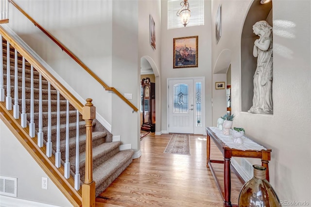 foyer with arched walkways, visible vents, a wealth of natural light, and light wood-style floors