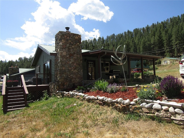 57920 US Highway 285 Unit 10, Bailey, CO 80421 - view of side of home with a chimney, a wooden deck, a metal roof, and a forest view