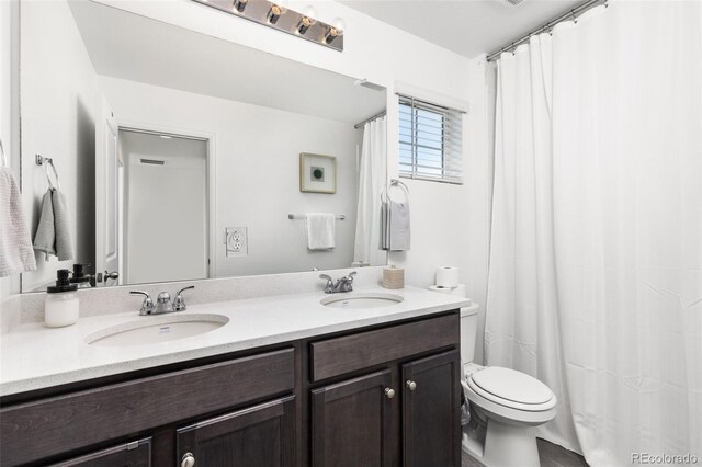 full bathroom with double vanity, toilet, and a sink