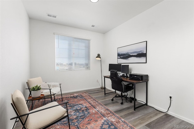 office area with wood finished floors, visible vents, and baseboards