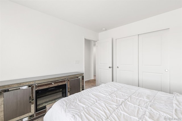 carpeted bedroom with a closet and a fireplace