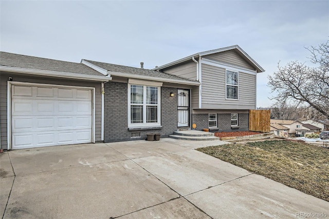 split level home featuring a garage, concrete driveway, and brick siding