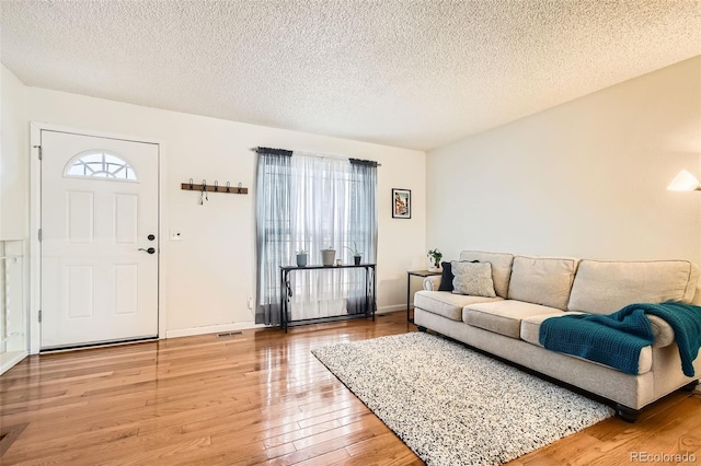 living area with a healthy amount of sunlight, a textured ceiling, baseboards, and wood finished floors