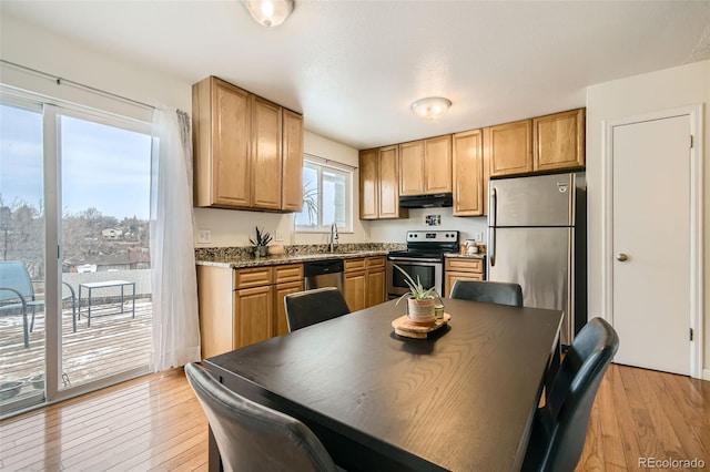 kitchen featuring stainless steel appliances, light stone counters, light wood-style flooring, and under cabinet range hood