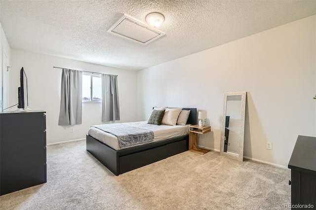 bedroom featuring light carpet, attic access, baseboards, and a textured ceiling