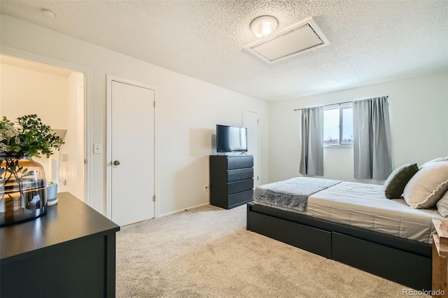 bedroom featuring attic access, light carpet, and a textured ceiling