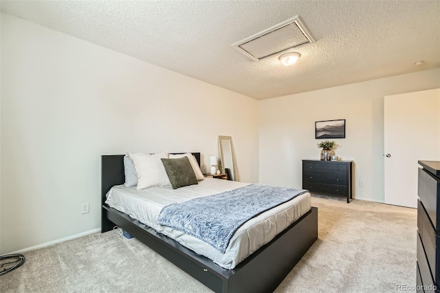 bedroom featuring light carpet, attic access, and a textured ceiling