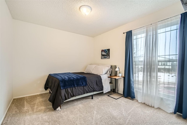 carpeted bedroom featuring a textured ceiling and baseboards