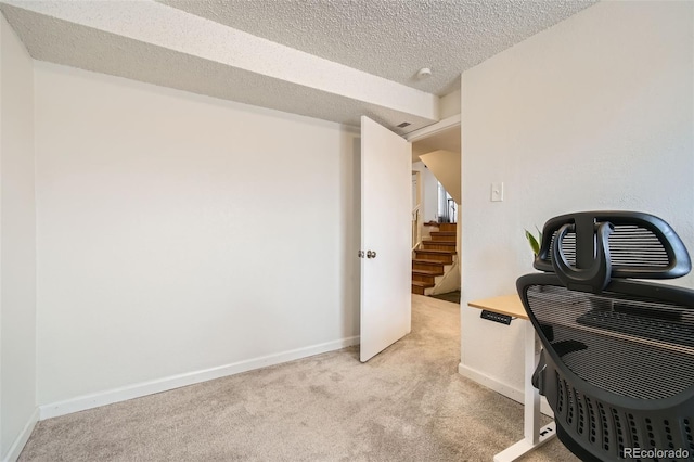 office area with baseboards, a textured ceiling, and light colored carpet