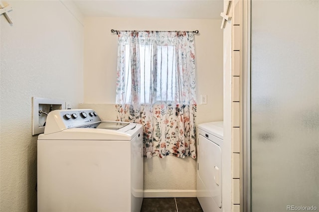 washroom with washing machine and dryer, laundry area, dark tile patterned floors, and baseboards