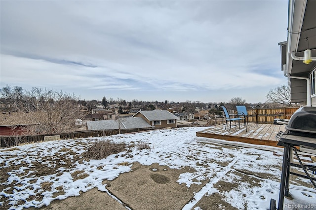 yard covered in snow with a residential view and fence