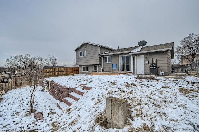 snow covered rear of property featuring fence