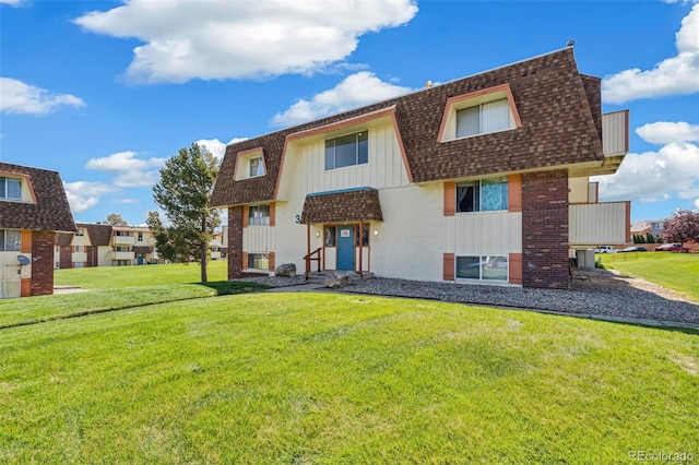 10211 Ura Ln Unit 3-104, Thornton, CO 80260 - rear view of property featuring roof with shingles, mansard roof, brick siding, and a yard