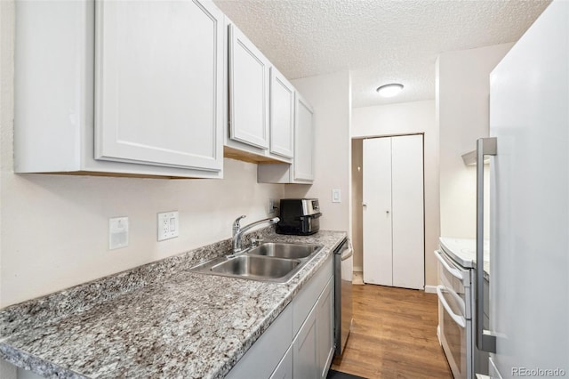 10211 Ura Ln Unit 3-104, Thornton, CO 80260 - kitchen with a sink, white appliances, light wood-style flooring, a textured ceiling, and light countertops
