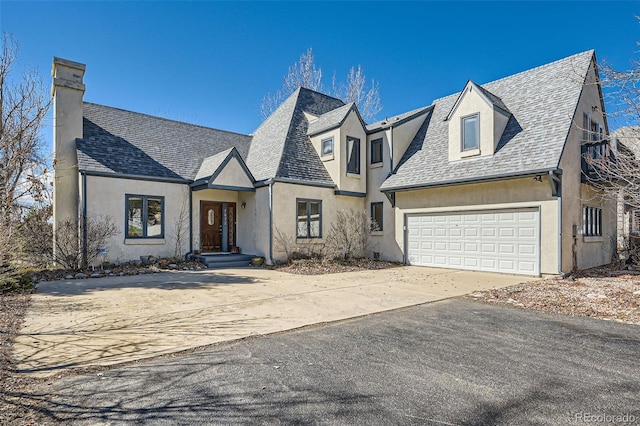 view of front of home with driveway, roof with shingles, an attached garage, and stucco siding