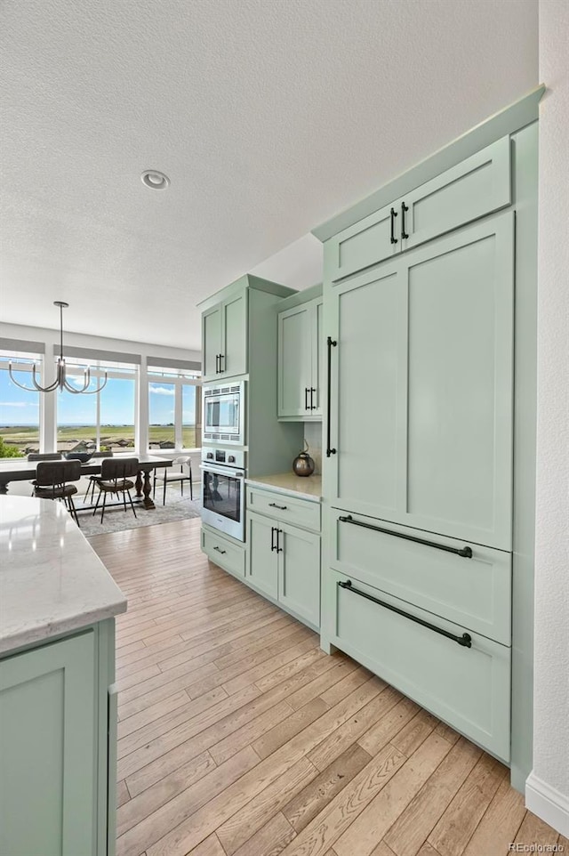 9510 Orion Way, Arvada, CO 80007 - kitchen featuring green cabinets, appliances with stainless steel finishes, plenty of natural light, light wood finished floors, and a textured ceiling