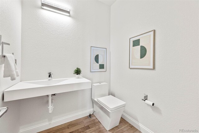 9510 Orion Way, Arvada, CO 80007 - bathroom with toilet, wood finished floors, baseboards, and a sink