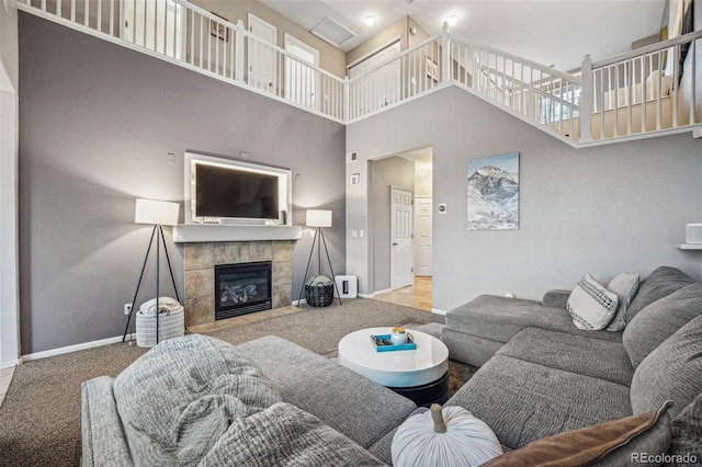 living room featuring a tiled fireplace, carpet floors, and a towering ceiling