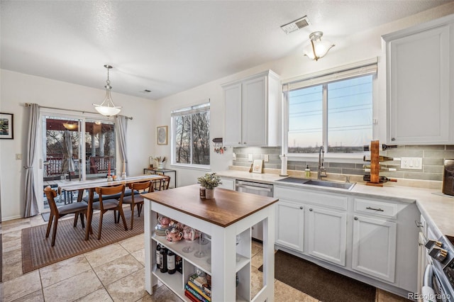 kitchen with backsplash, sink, white cabinetry, hanging light fixtures, and stainless steel appliances