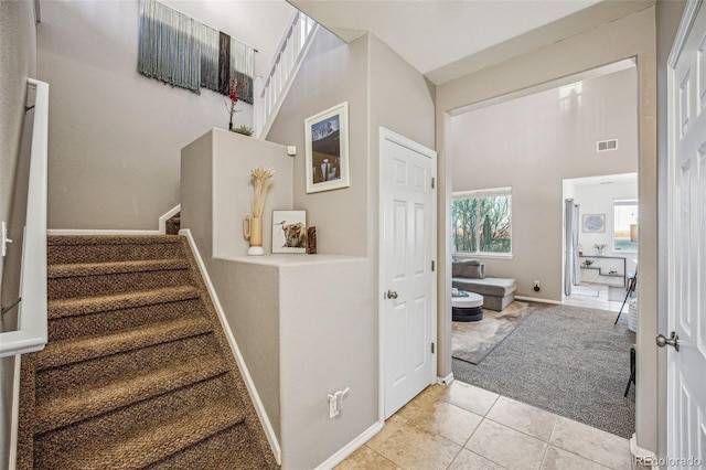 staircase with a high ceiling and carpet flooring