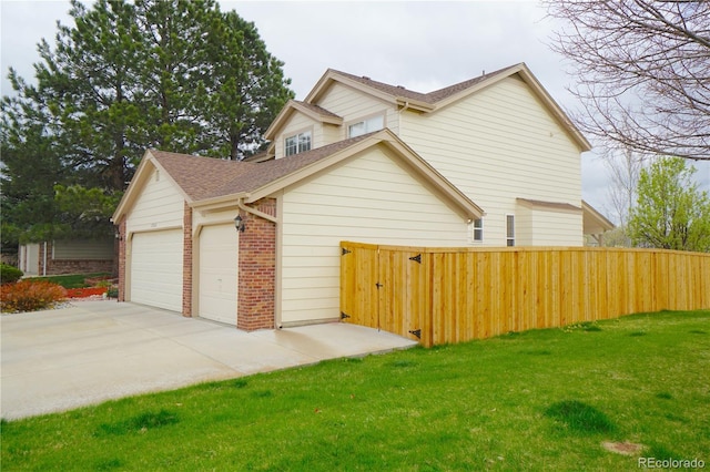 view of home's exterior with a lawn, brick siding, fence, a garage, and a shingled roof