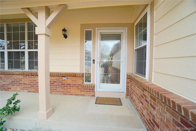 entrance to property with a porch and brick siding