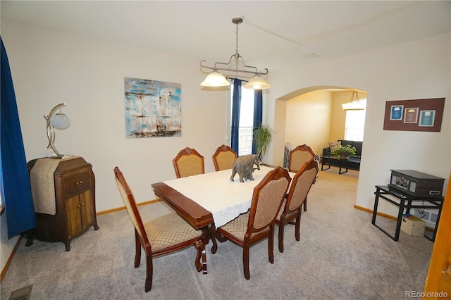 dining area with light carpet, arched walkways, and baseboards