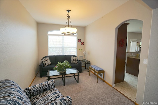living area with light colored carpet, an inviting chandelier, and arched walkways