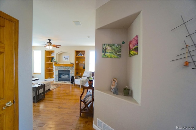 corridor with light wood-style flooring, visible vents, and built in shelves