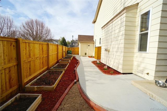 view of side of property featuring a fenced backyard, a patio area, and a vegetable garden