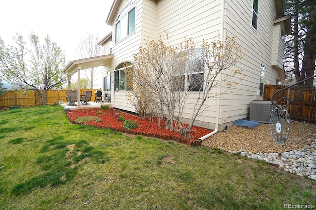 view of side of home with a yard, central air condition unit, a patio, and a fenced backyard