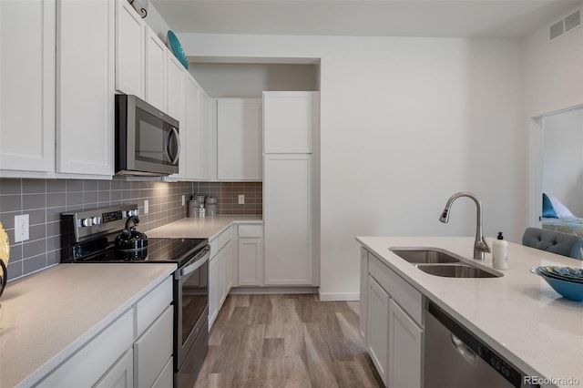 kitchen featuring stainless steel appliances, sink, white cabinets, and decorative backsplash