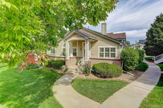 bungalow-style house featuring a chimney, a front lawn, and brick siding