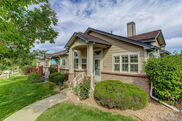 bungalow-style home with a chimney, a front lawn, and brick siding