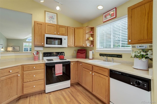 kitchen featuring white appliances, a sink, light wood-style floors, vaulted ceiling, and light countertops