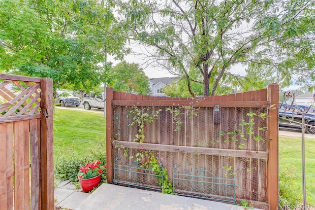 view of gate with a yard and fence